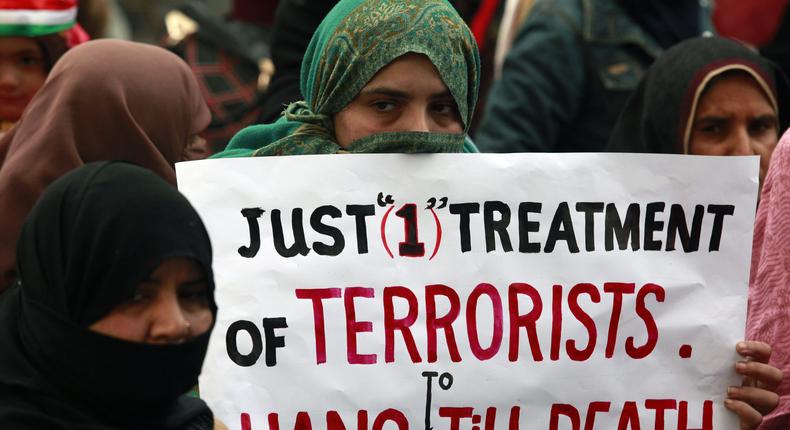 A supporter of political party Pakistan Awami Tehreek (PAT), holds a sign with others to condemn the attack by Taliban gunmen on the Army Public School in Peshawar, during a rally in Lahore December 21, 2014. 