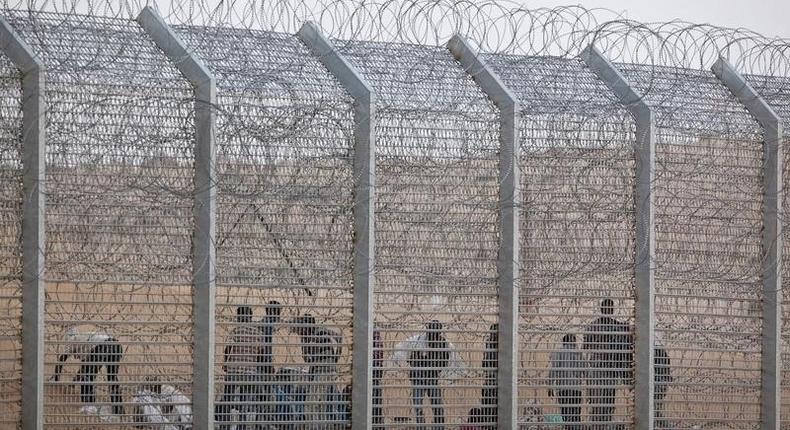 African would-be immigrants stand near the border fence between Israel and Egypt near the Israeli village of Be'er Milcha in a file photo. REUTERS/ Nir Elias