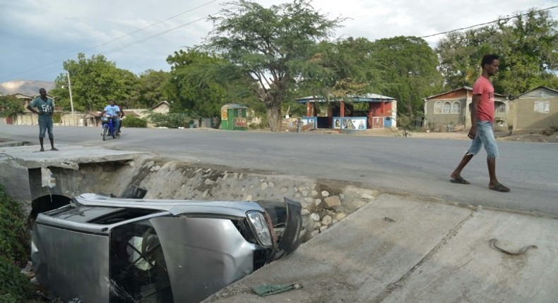 A car damaged by a bus lies on the side of a road in Gonaives