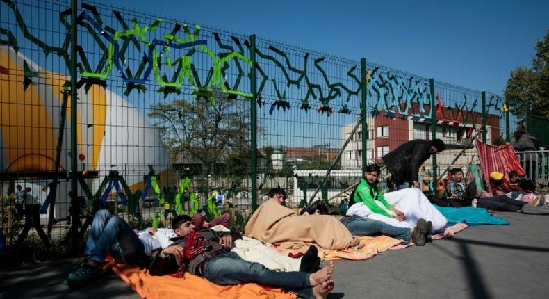 Migrants lay on the ground at the entrance of a migrant and refugee camp near Porte de la Chapelle, northern Paris, on April 19, 2017