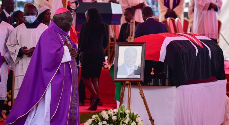 A bishop walks to the flag draped coffin for former Kenyan President Mwai Kibaki as he lies in state during the memorial service at the Nyayo National Stadium in Nairobi on April 29, 2022. (Photo by TONY KARUMBA/AFP via Getty Images)