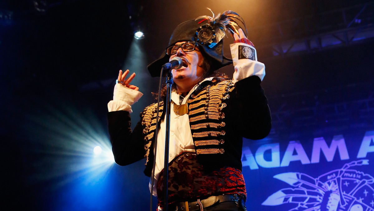 Adam Ant wita mnie w drzwiach swego biura w zachodnim Londynie, ubrany w ciemne kapcie, obcisłe czarne spodnie, granatową koszulę z bufiastymi rękawami w XVIII-wiecznym stylu, elegancką, aksamitną dwurzędową marynarkę i czerwoną chustkę na głowę. — Ładny strój w pracy to dla mnie podstawa — podkreśla.