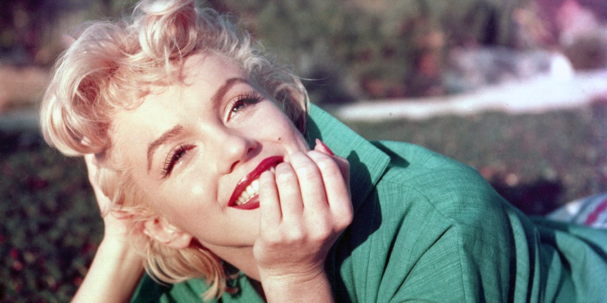 Actress Marilyn Monroe poses for a portrait laying on the grass in 1954 in Palm Springs, California.