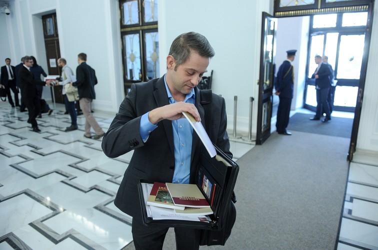 Poseł PO Tomasz Cimoszewicz prezentuje zawartość teczki z materiałami dla nowych posłów