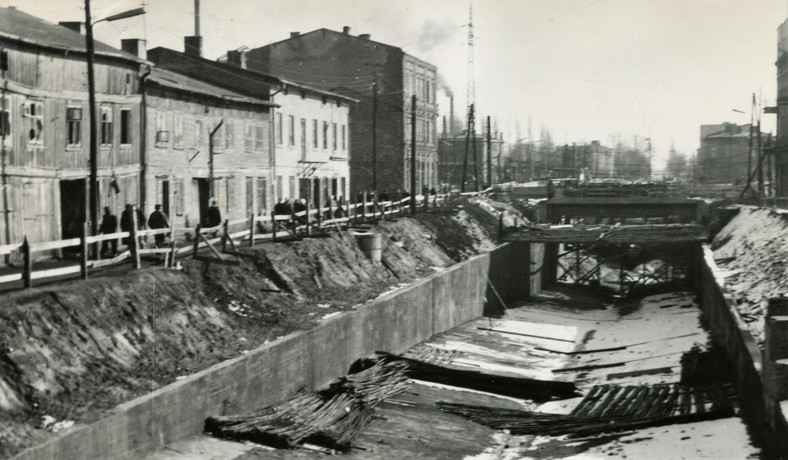 Budowa tunelu drogowego pod przejazdem kolejowym linii Warszawa-Łódź w Żyrardowie i widoczne po lewej stronie rozpadające się "drewniaki", zdjęcie z drugiej połowy lat 60.