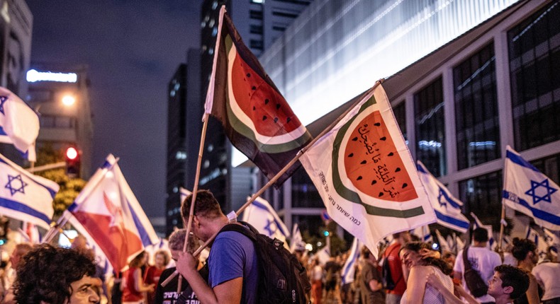 A protester in Tel Aviv carries flags with watermelon illustrations, symbolizing the Palestinian flag.Anadolu Agency