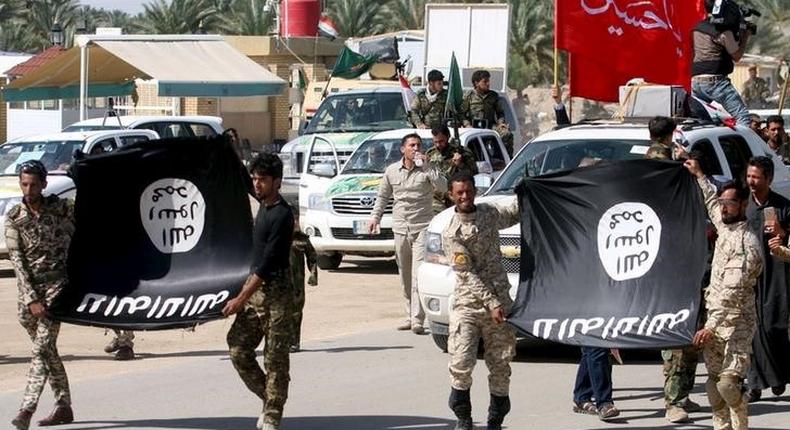 Shi'ite paramilitary fighters hold an Islamist State flag which they pulled down during victory celebrations after returning from Tikrit in Kerbala, southwest of Baghdad April 4, 2015.     REUTERS/Mushtaq Muhammed