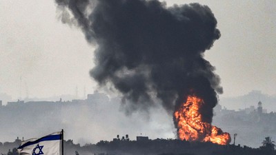 An Israeli flag flies in southern Israel as a fireball erupts across the border in the Gaza Strip.RONALDO SCHEMIDT/AFP via Getty Images