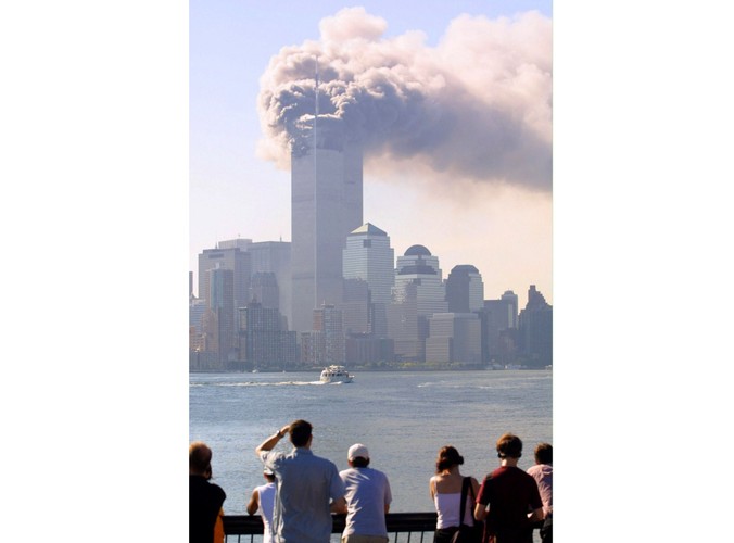 Ludzie stojący nad brzegiem rzeki Hudson obserwują jedną z płonących wież World Trade Center w Nowym Jorku, chwilę po uderzeniu w nią jednego z porwanych samolotów