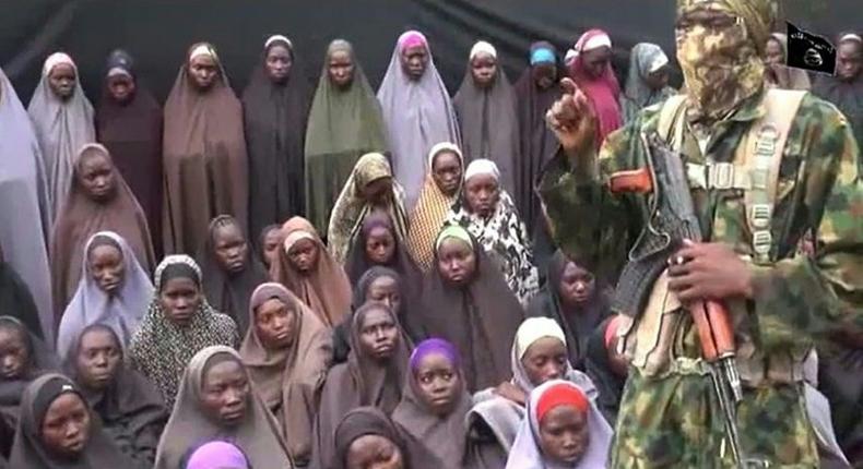 This video grab image created on August 14, 2016 taken from a video released on Youtube purportedly by Boko Haram showing what is claimed to be one of the groups fighters at an undisclosed location standing in front of alleged Chinok Girls 
