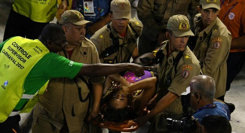 Firefighters assist a reveller of the Unidos da Tijuca samba school at the Sambadrome in Rio de Janeiro early on February 28, 2017, after the third floor of an allegorical car collapsed during the second night of Rio Carnival