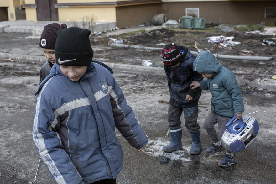 Ukraińskie dzieci, wśród nich trójka sierot, spacerują po ulicy w mieście Bucza