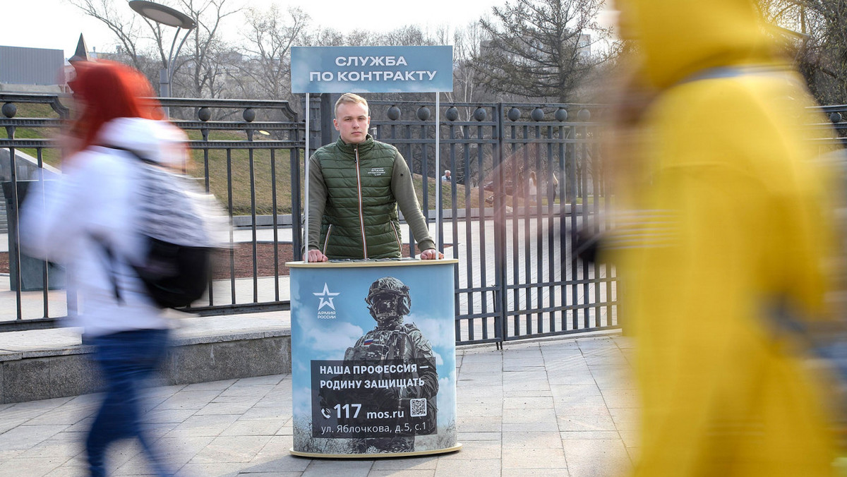 Rozdawanie ulotek przed wejściem do parku w Moskwie. Napis nad stoiskiem: "Służba kontraktowa". Napis na plakacie z rosyjskim żołnierzem: "Nasz zawód — bronić ojczyzny"