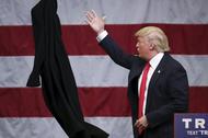 U.S. Republican presidential candidate Donald Trump tosses off his overcoat as he speaks at a campai