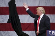 U.S. Republican presidential candidate Donald Trump tosses off his overcoat as he speaks at a campai