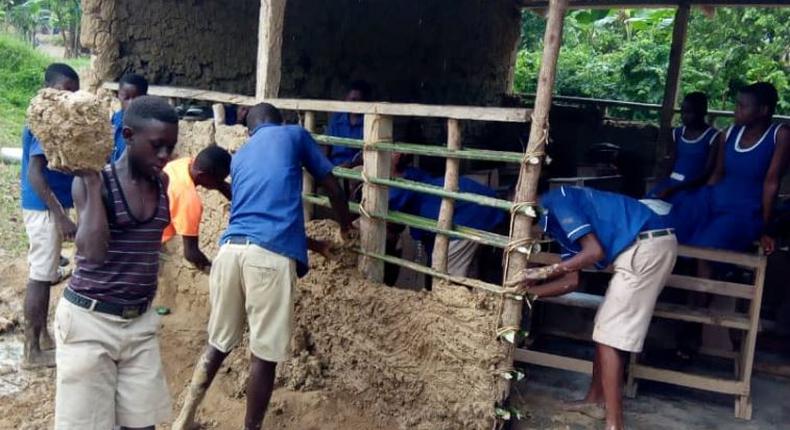 Pupils mould blocks with mud to construct their classroom