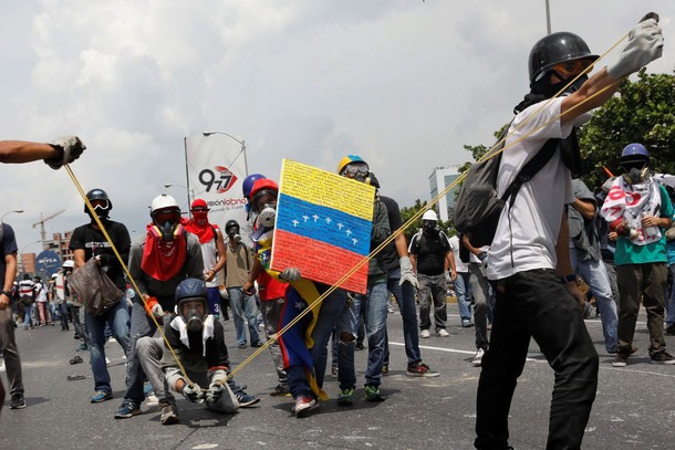 Opposition supporters uses a giant sling shot to throw a Poopootovs, a bottle filled with feces, w