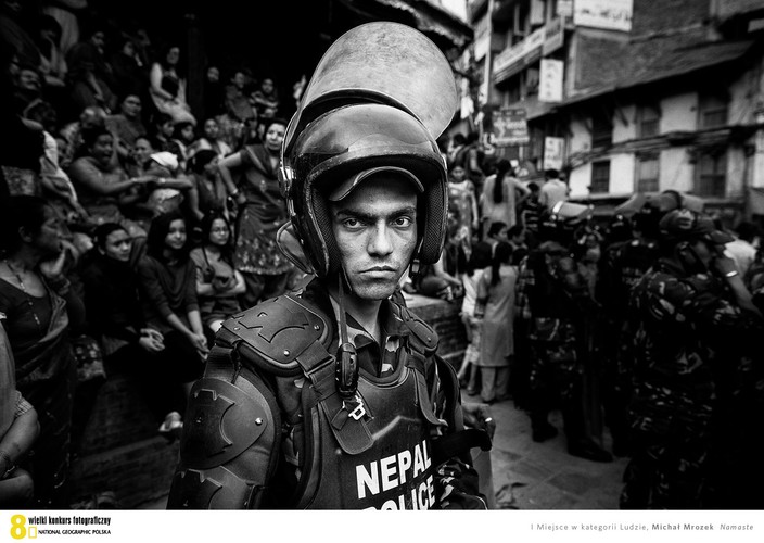 Kategoria ludzie - Michał Mrozek ,,Namaste’’  Nepal, Katmandu. Policjant w pełnym rynsztunku zabezpieczający przejście tłumu  i powozu-świątyni podczas festiwalu Seto Machhendranath na ulicach miasta. Podczas tego rodzaju świąt, których w Katmandu  nie brakuje, na ulicach gromadzą się tysiące ludzi. Wspólne świętowanie jednych  to jednocześnie wymagająca skupienia praca drugich.