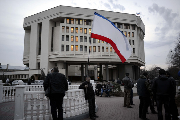 Mężczyzna z flagą Republiki Autonomicznej Krymu przed siedzibą parlamentu w Symferopolu. Fot. PAP/Jakub Kamiński