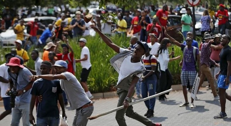 Students throw stones during a confrontation with security guards as they protest over planned increases in tuition fees outside the (UJ) University of Johannesburg October 22, 2015. REUTERS/Siphiwe Sibeko