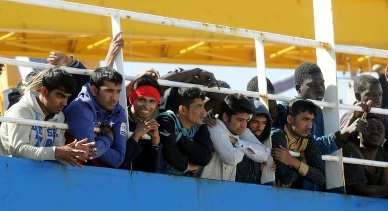 Men wait on deck of a merchant ship at their arrival along with 470 migrants and refugees after being rescued at sea off the Libyan coasts, on April 18, 2017