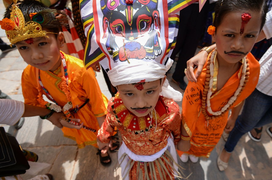 Nepalskie dziecko ubrane w tradycyjny strój krowy pozuje z innymi, biorąc udział w procesji na festiwal krów Gai Jatra w Katmandu