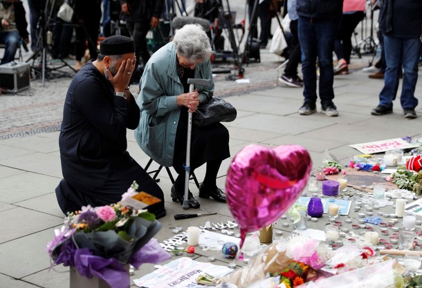 A Jewish woman named Renee Rachel Black and a Muslim man named Sadiq Patel react next to floral trib