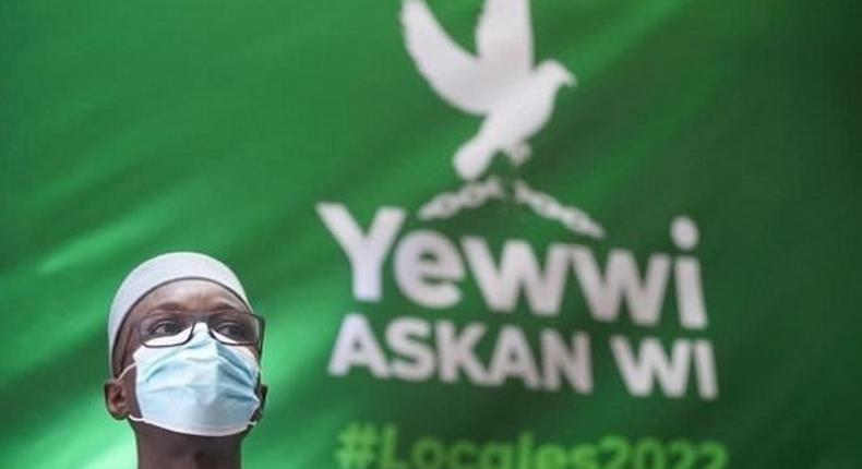 Ousmane Sonko devant une banderole avec le logo de la coalition Yewwi Askanwi