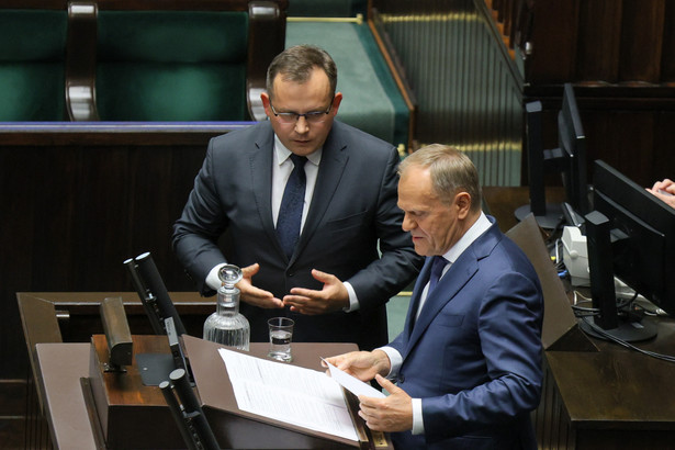 Premier Donald Tusk (P) i poseł PiS Paweł Rychlik (C) na sali obrad Sejmu w Warszawie