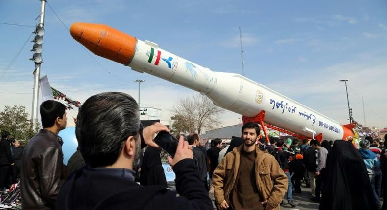 Iranians take pictures of the Simorgh satellite rocket during celebrations in Tehran to mark the 37th anniversary of the Islamic revolution on February 11, 2016