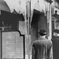 Germans pass by the smashed windows of a Jewish-owned shop. The aftermath of Kristallnacht (Night of