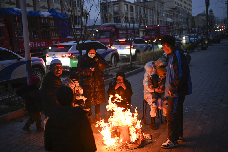 Ludzie gromadzący się palącego się przedmiotu na ulicy po trzęsieniu ziemi w prowincji Gansu w Chinach, 19 grudnia 2023 r.