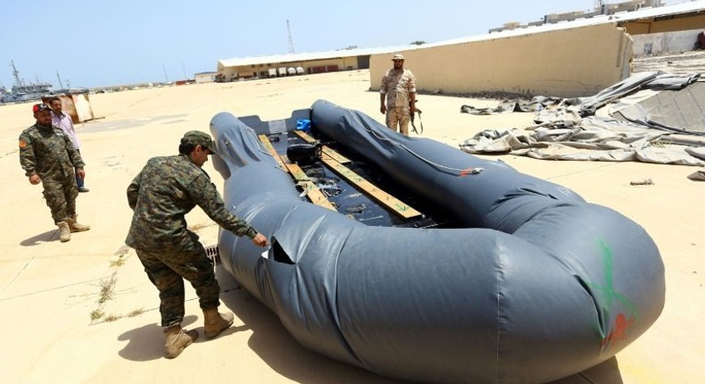 A Libyan naval officer punctures a dinghy used by Illegal migrants, after they were rescued by the Libyan coastguard in the Mediterranean Sea on May 6, 2017