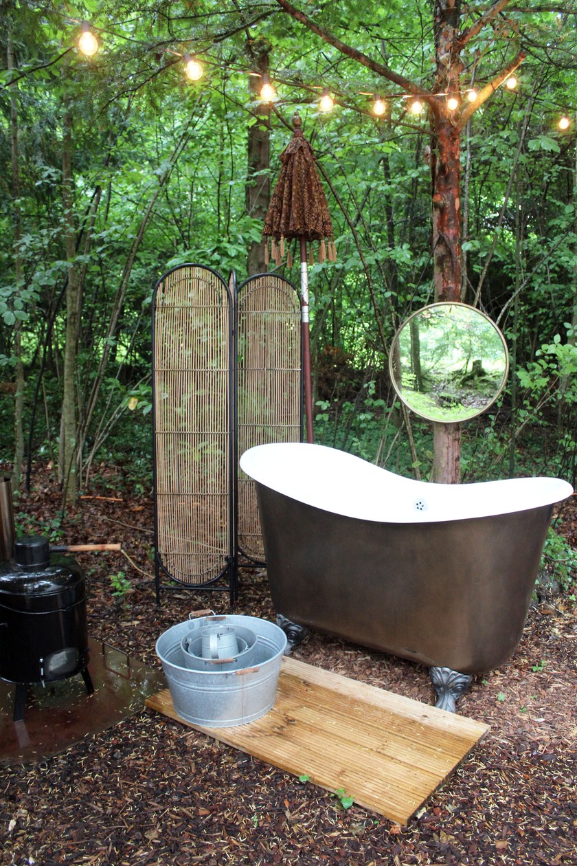 Une baignoire est installée derrière la tente, permettant aux hôtes de prendre un bain en extérieur, sous les arbres. 