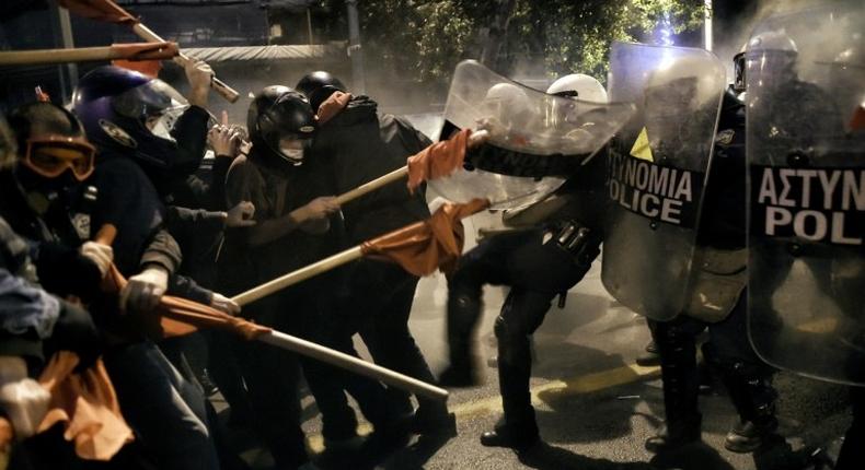 Demonstrators holding red flags clash with Greek riot police during a protest against the visit of the US president in Athens on November 15, 2016