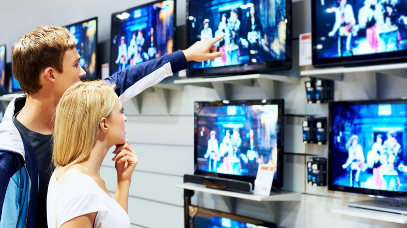 Young couple in megastore looking at TVs