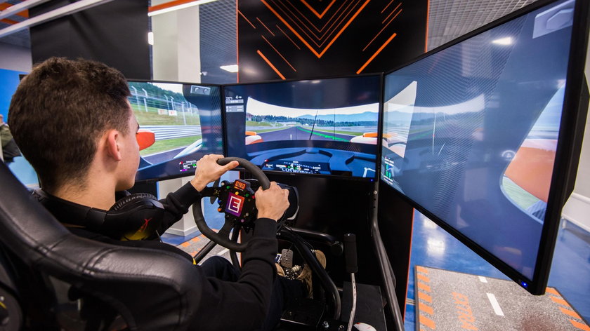 MOSCOW, RUSSIA - OCTOBER 27 2018. Young man plays on a computer racing simulator with big screens