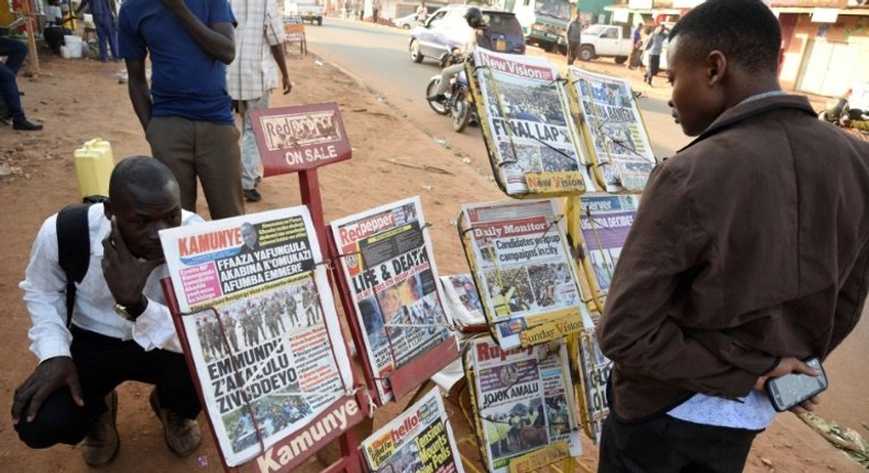 A man reads newspaper headlines at a Kampala news-stand