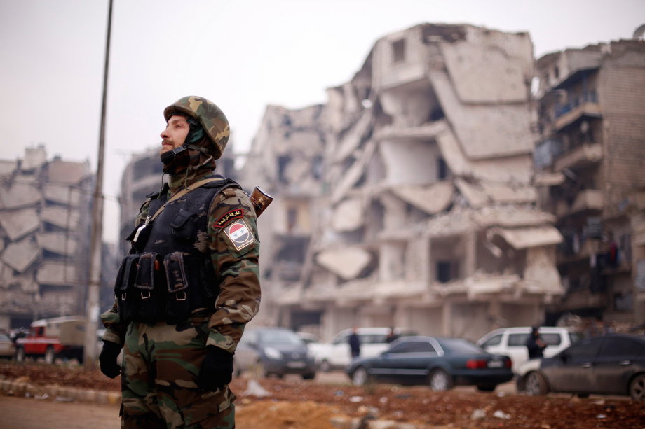 A member of forces loyal to Syria's President Bashar al-Assad stands near damaged buildings in Aleppo's Salaheddine district, Syria December 16, 2016.