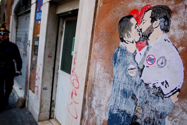 An Italian Carabiniere stands next to a mural depicting Northern League's leader Matteo Salvini and 