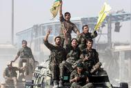 Syrian Democratic Forces (SDF) fighters ride atop of military vehicles as they celebrate victory in Raqqa