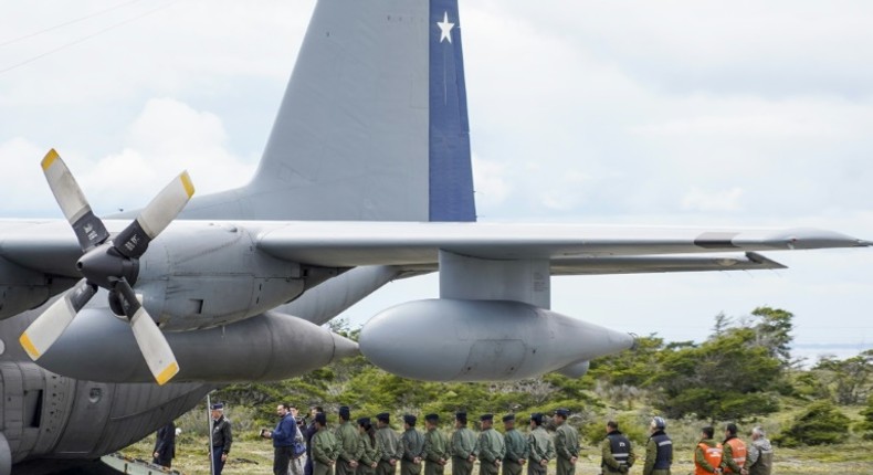 Chilean military personnel stand by an Air Force plane as they wait to unload human remains found during the search for the C-130 Hercules transport plane that crashed in the sea on its way to Antarctica