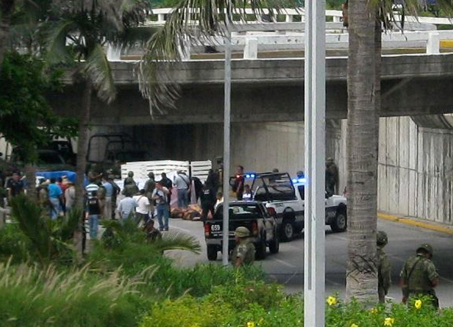 Police and a forensic team stand around bodies on a motorway in Boca del Rio, on the outskirts of Veracruz, September 20, 2011. The bodies of 35 people with suspected links to organized crime were found on a highway underpass, the local prosecutor said.