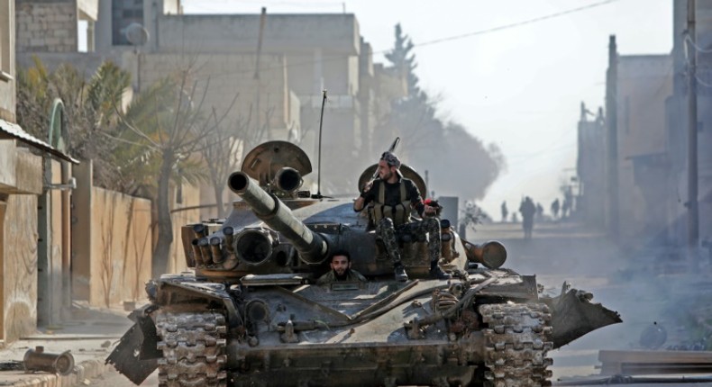 Turkey-backed Syrian fighters ride a tank in the town of Saraqib in the eastern part of the Idlib province in northwestern Syria