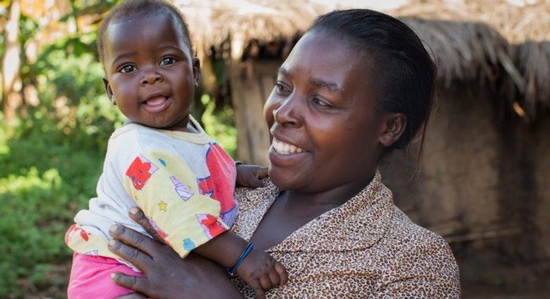 A woman and her child standing outside her home.