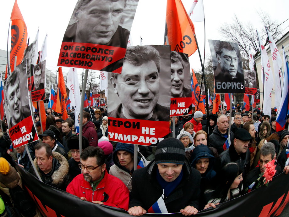 People hold flags and posters during a march to commemorate Kremlin critic Boris Nemtsov, who was shot dead on Friday night in central Moscow on March 1, 2015.