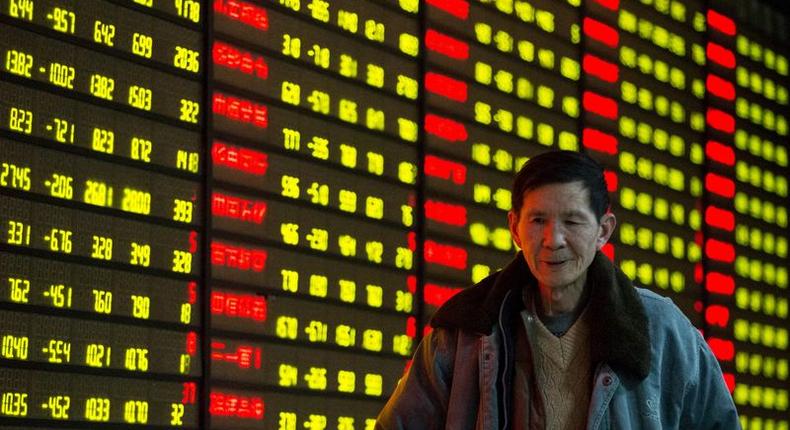 An investor walks past an electronic screen showing stock information at brokerage house in Nanjing, Jiangsu Province, China, January 11, 2016. REUTERS/China Daily