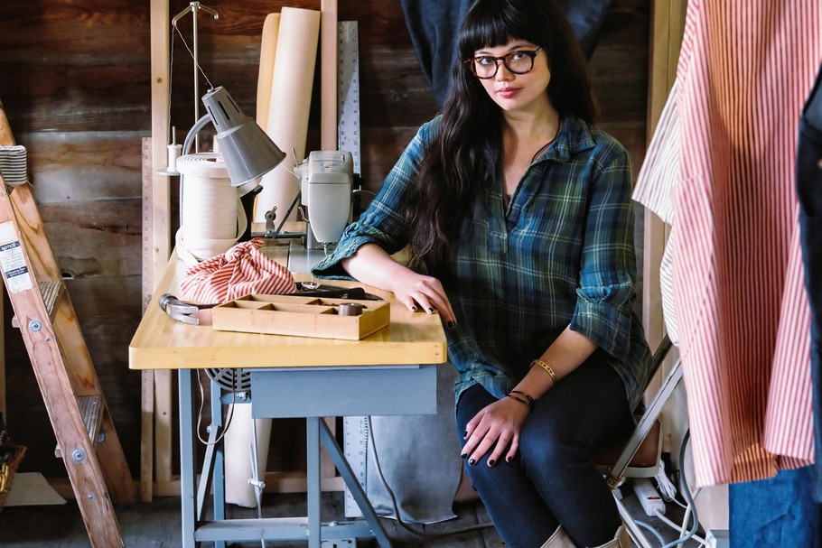 Mixed race seamstress sitting at sewing machine in studio