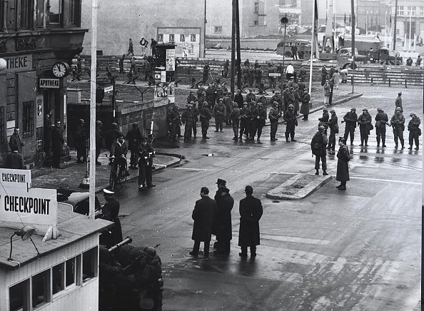 Za grubą barierą wyposażonej w sprzęt wojskowy Volksarmii policja i robotnicy budowlani wznoszą barierę czołgową na przejściu granicznym "Friedrichstrasse"