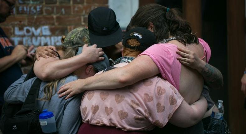 Mourners embrace next to a makeshift memorial to Heather Heyer in Charlottesville, Virginia, on the one year anniversary of her death at the hands of a white supremacist in a speeding car